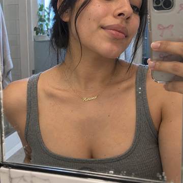Mariana usando su collar dorado personalizado frente al espejo